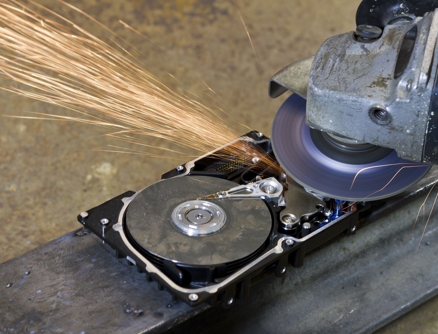 A hard disk drive is being destroyed by an electronic saw or grinder