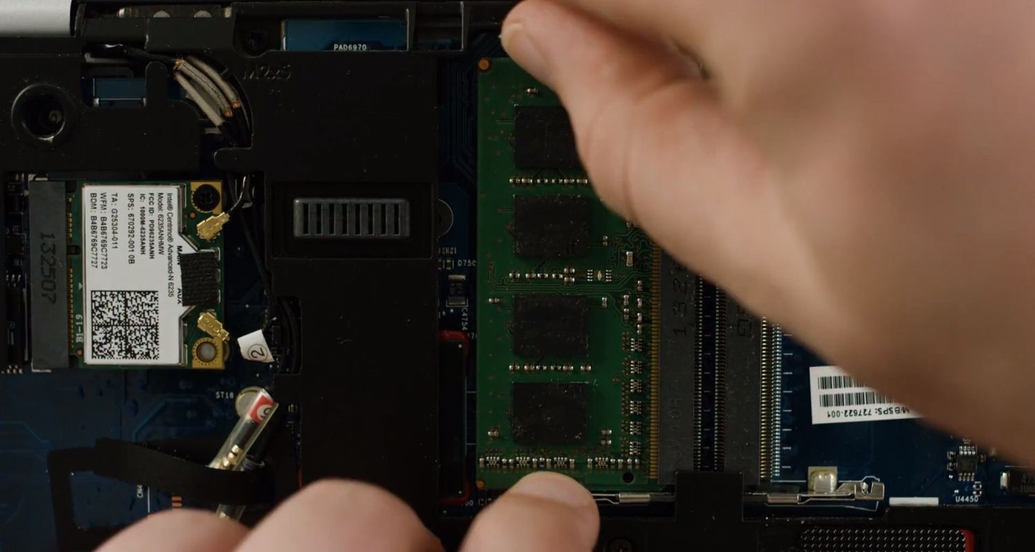 Person unclipping a RAM memory module from the inside of a laptop