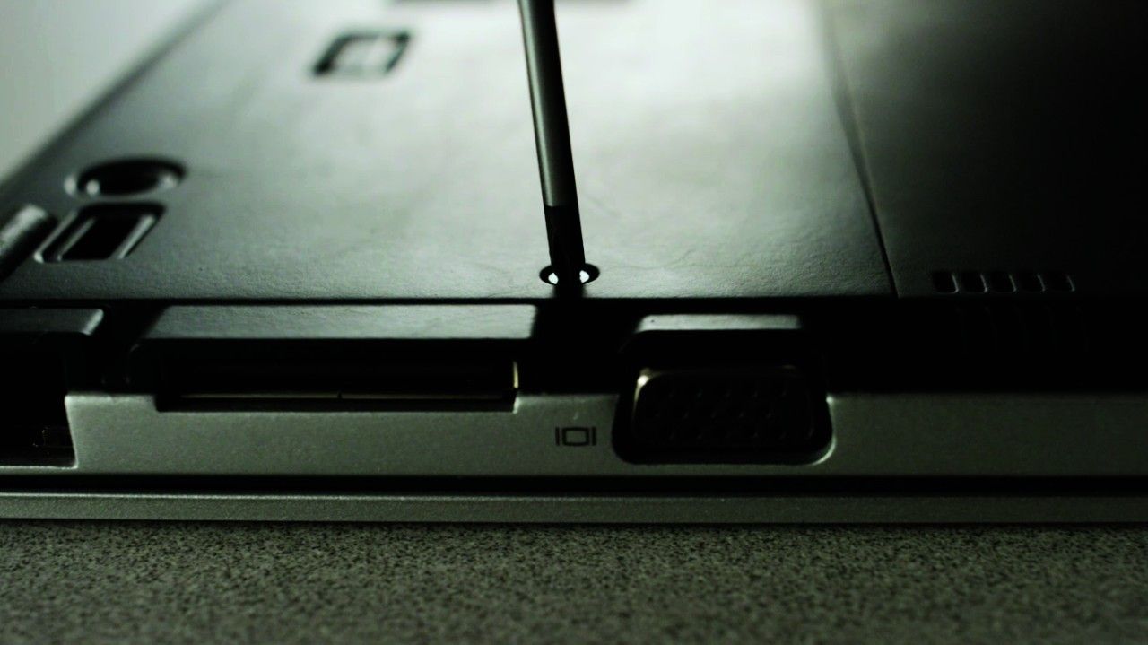 Screwdriver removing screw from back of laptop
