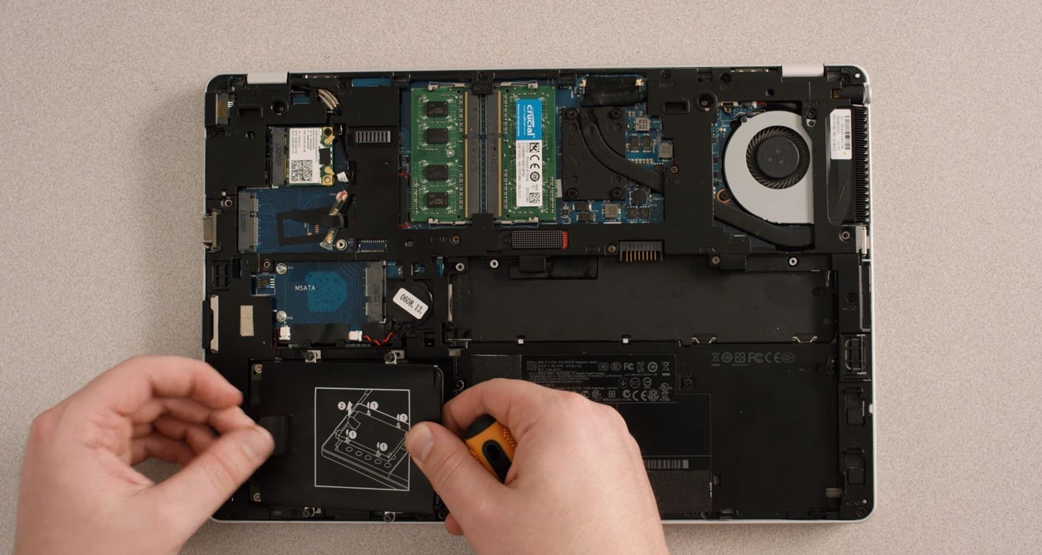 Person removing the storage drive from the inside of a laptop